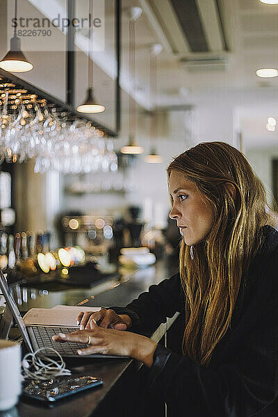 Seitenansicht einer Geschäftsfrau mit Laptop an der Theke