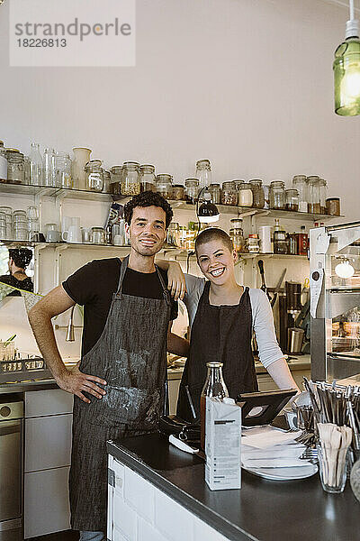Porträt von glücklichen männlichen und weiblichen Geschäftsinhabern  die zusammen in einem Café stehen