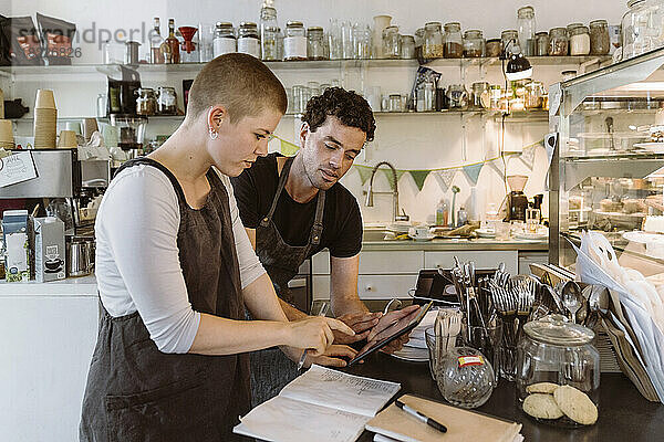 Männliche und weibliche Besitzer machen eine Inventur mit einem Tablet-PC in einem Cafe