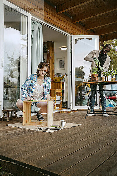 Junge Frau baut Möbel mit Mann bei der Gartenarbeit auf der Veranda