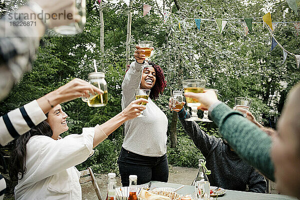 Fröhliche Freunde stoßen während einer Dinnerparty mit Getränken an