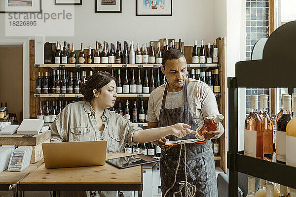 Ein Mann und eine Frau unterhalten sich in einem Geschäft über eine Weinflasche