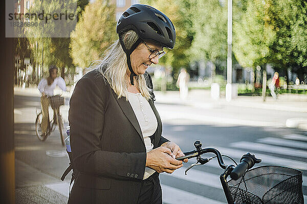 Geschäftsfrau mit Fahrradhelm und Smartphone