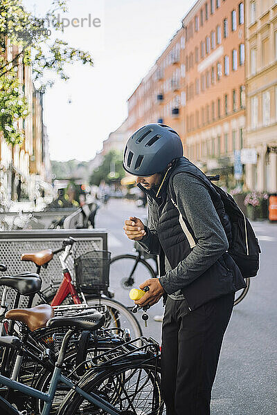 Geschäftsmann  der mit seinem Smartphone telefoniert  während er in der Nähe eines Fahrrads an einer Parkstation steht