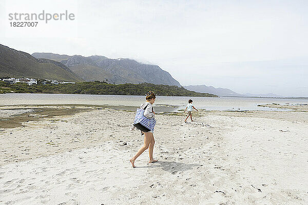 Südafrika  Hermanus  Teenager-Mädchen (16-17) mit Bruder (8-9) beim Spaziergang am Sandstrand