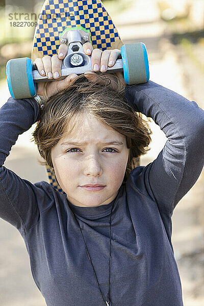 Porträt eines Jungen (8-9) mit Skateboard