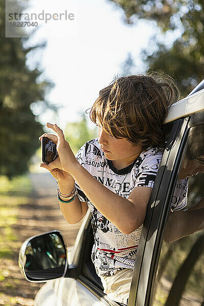 Junge (8-9) fotografiert aus dem Auto