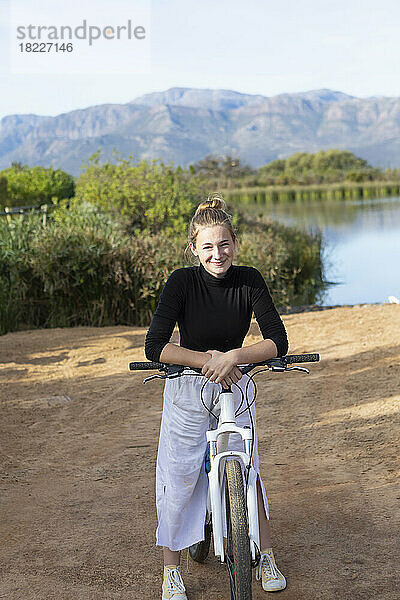 Südafrika  Stellenbosch  Porträt eines lächelnden Teenager-Mädchens (16-17) auf dem Fahrrad