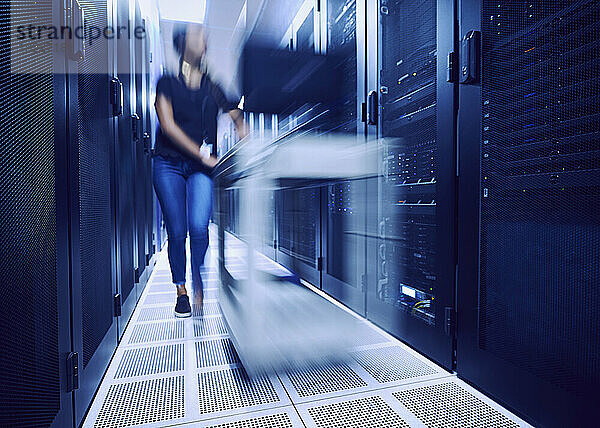 Eine Technikerin läuft verschwommen durch den Serverraum