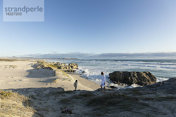 Südafrika  Hermanus  Teenager-Mädchen (16-17) mit jüngerem Bruder (8-9) klettert auf Felsen am Strand