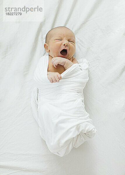 Draufsicht auf einen neugeborenen Jungen (0–1 Monat)  der in eine Decke gewickelt ist