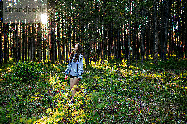 Teenager-Mädchen im Wald hält einen Schläger und schaut nach oben