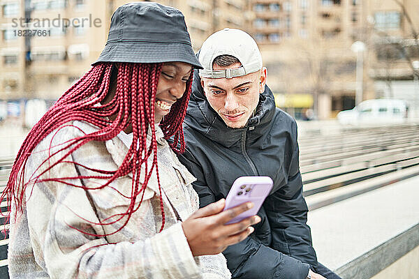 Porträt eines multiethnischen Paares  das auf der Straße telefoniert