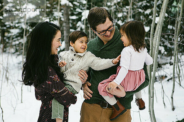 Eine gemischtrassige Familie lacht und kitzelt im verschneiten Ort