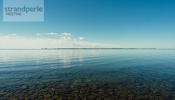 Ruhiges Wasser des Ontariosees an einem sonnigen Tag  aufgenommen vom Ufer aus.