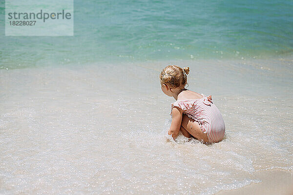 Kleines Mädchen spielt in den Meereswellen am Strand