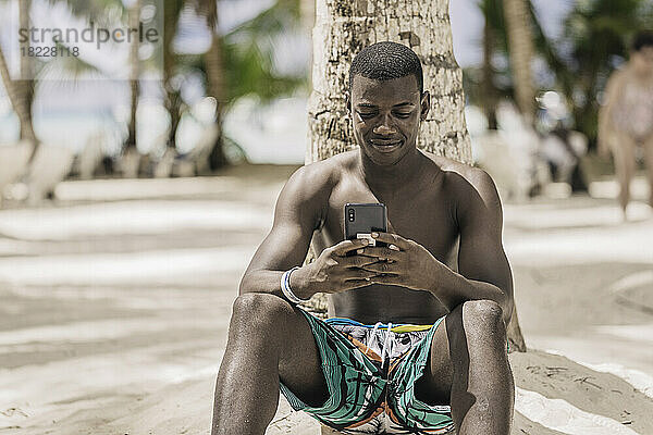 Afroamerikanischer Mann benutzt Smartphone in der Nähe der Handfläche