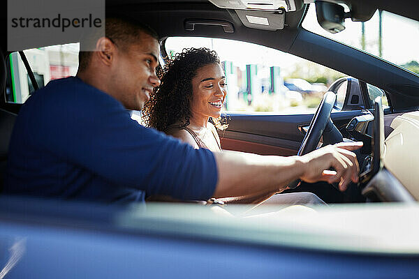 Lächelndes Paar nutzt GPS  während es im Elektroauto sitzt