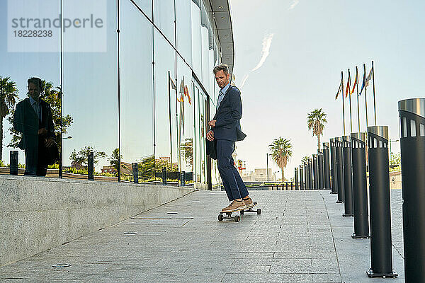 Moderner Geschäftsmann geht auf einem Skateboard zur Arbeit.