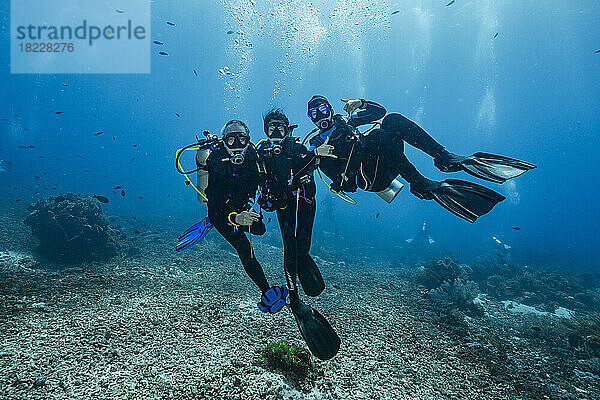 Tauchfreunde posieren unter Wasser in der Nähe der Insel Flores in Komodo