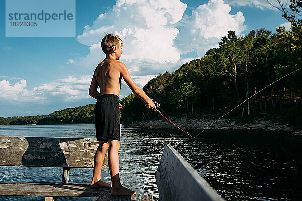 Kleiner Junge fischt an einem sonnigen Sommertag vom Dock aus