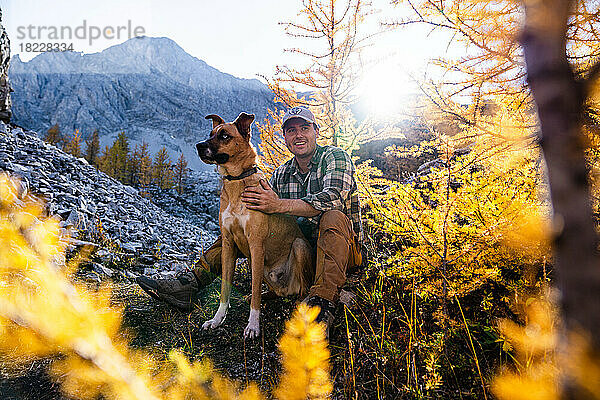 Mann mit seinem besten Freund auf einer Wanderung bei Sonnenuntergang