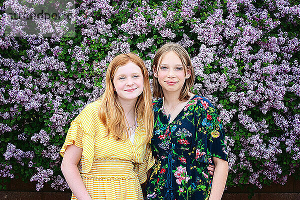 Zwei hübsche Teenager-Mädchen  umgeben von lila Blüten.