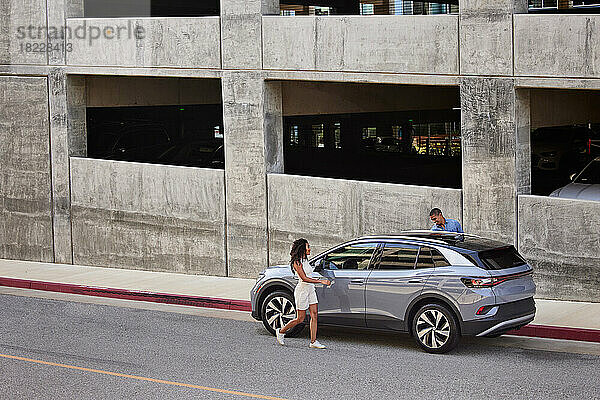 Paar steigt in auf Straße geparktes Elektroauto ein