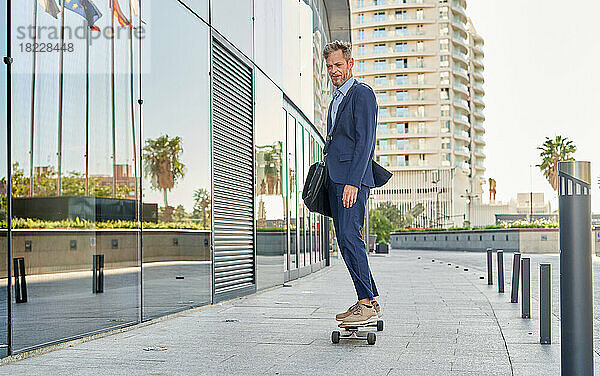 Junger Geschäftsmann geht auf einem Skateboard zur Arbeit