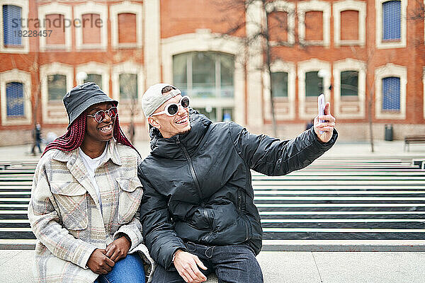 Multiethnisches Paar benutzt Telefon und macht Selfie auf der Straße