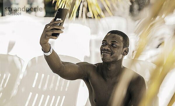 Fröhlicher schwarzer Tourist  der am Strand ein Selfie macht