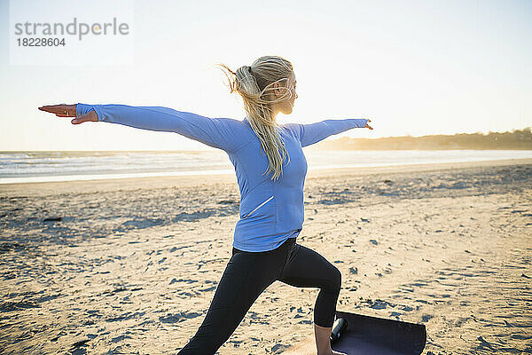 Junge Frau macht während der goldenen Stunde Yoga am Strand