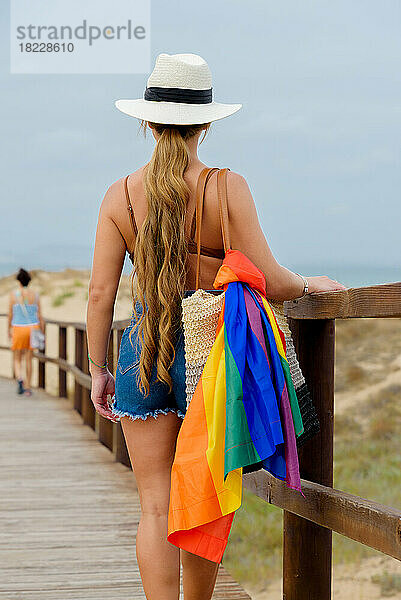 Mädchen geht mit der LGBT-Flagge in der Tasche zum Gay-Pride-Tag im Freien spazieren.