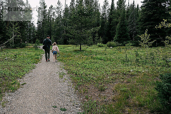 Vater und Tochter gehen auf Wanderweg im Wald