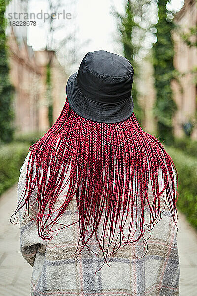 Nahaufnahme einer schwarzen Frau von hinten mit roten Haaren und Hut