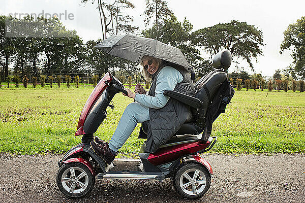 Rentnerin auf einem Elektroroller draußen im Regen