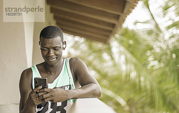 Schwarzer Mann benutzt Smartphone auf Terrasse