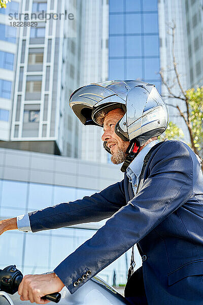 Moderner Geschäftsmann im Anzug  während er draußen auf dem Motorrad sitzt