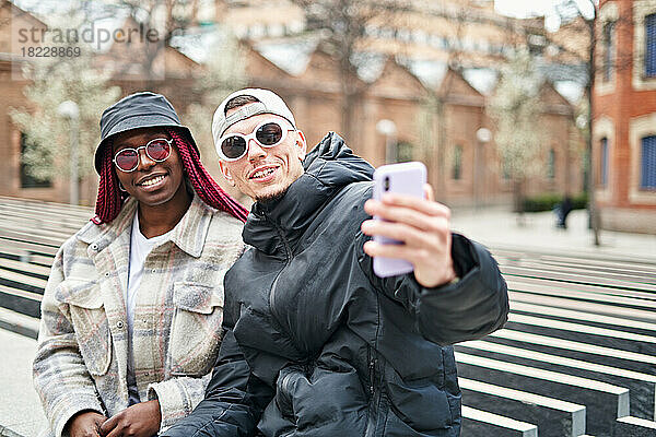 Multiethnisches Paar benutzt Telefon und macht Selfie auf der Straße