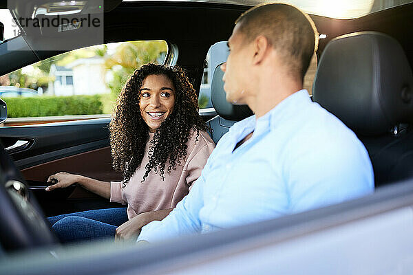 Lächelnde Frau spricht mit ihrem Freund  der im Auto sitzt