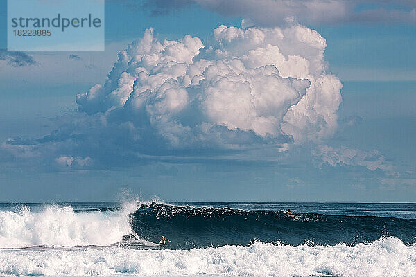 Männlicher Surfer auf der Welle unter Wolken