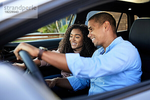 Glückliches Paar  das während der Autofahrt im Auto sitzt und einen Touchscreen nutzt