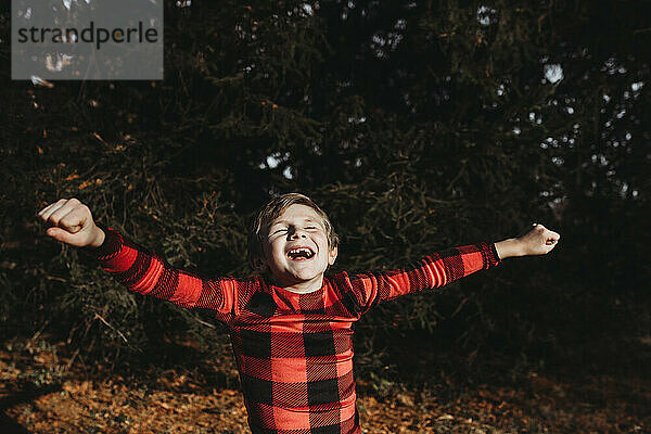 Kleiner Junge springt vor Freude im Weihnachtspyjama im Freien