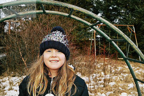 Fröhliches Mädchen auf verschneitem Spielplatz