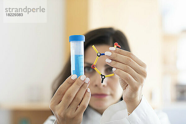 Chemiker hält Reagenzglas und Molekülmodell in der Hand  Fokus auf den Vordergrund