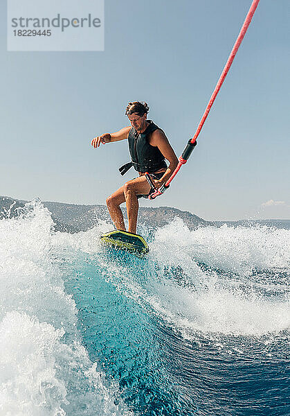 Mann beim Wakeboarden am See