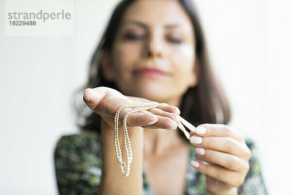 Frau hält Perlenkette  Fokus auf den Vordergrund