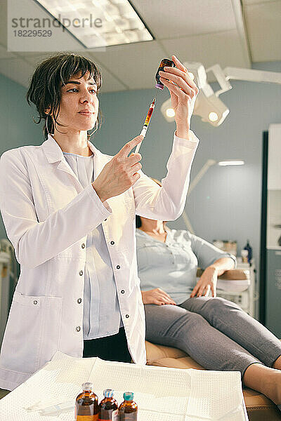 Ärztin bereitet eine Botox-Injektion vor  Patientin im Hintergrund