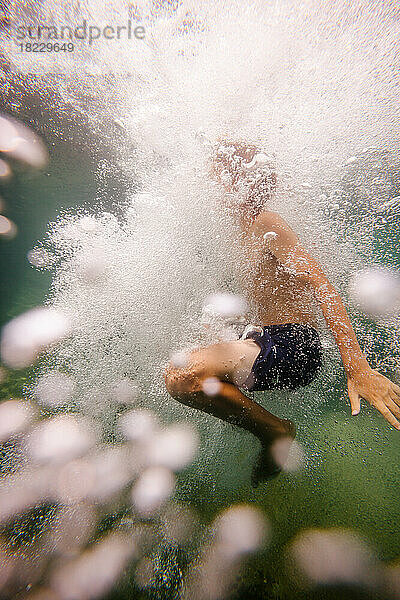 Junge (12-13) nach Sprung unter Wasser