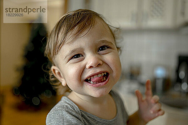 Cute little boy sticking out tongue at home